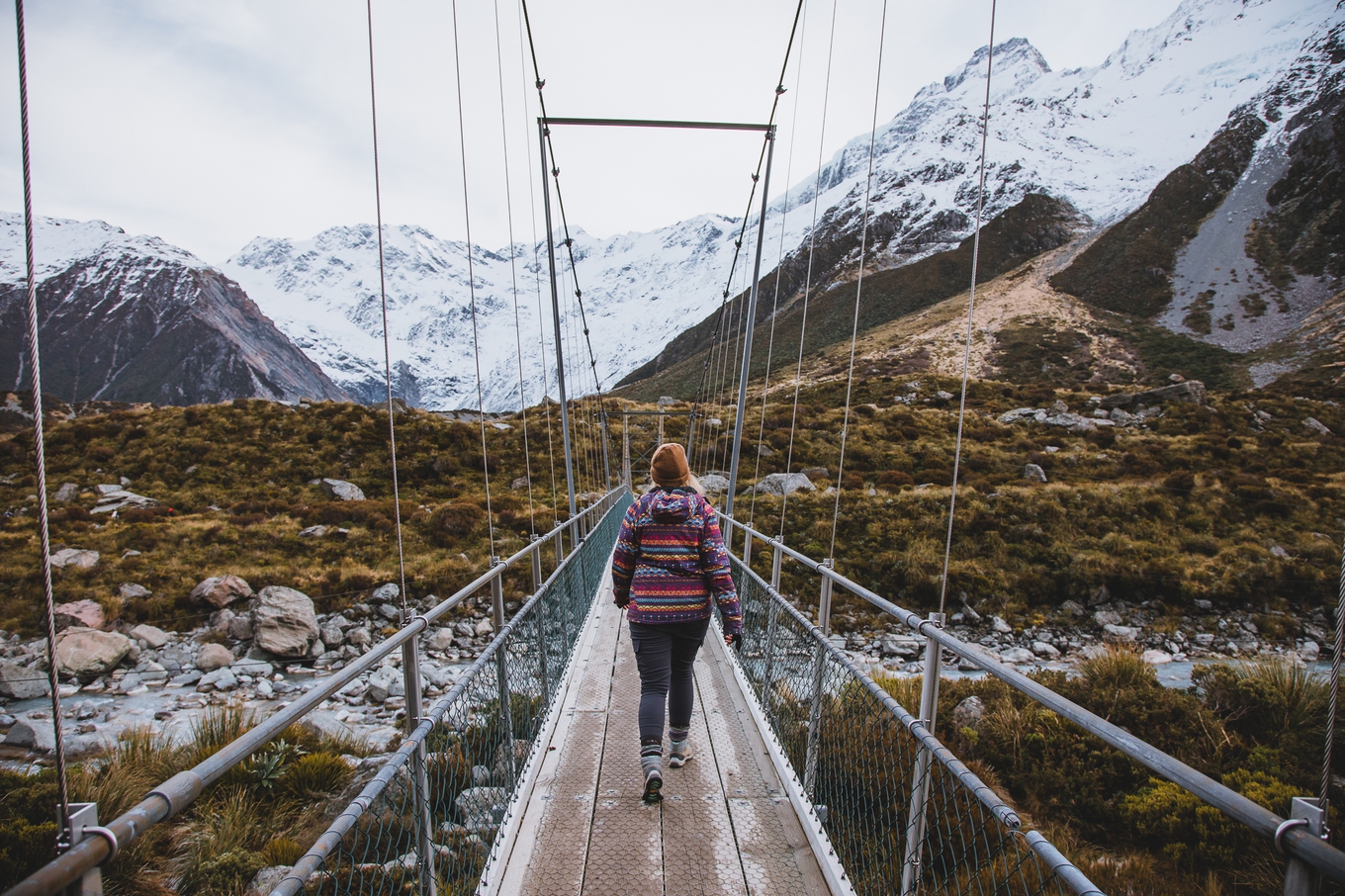 A woman on a hike; she is on a bridge with a mountain in the background